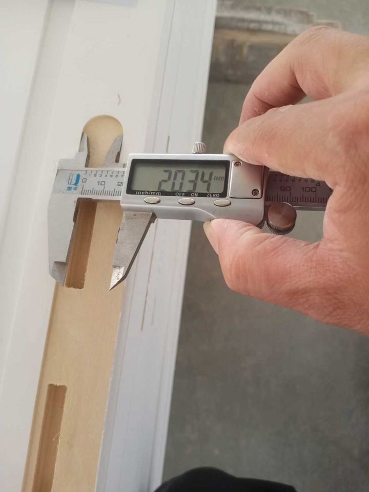 Digital caliper checking the dimension of a finished primed wood profile