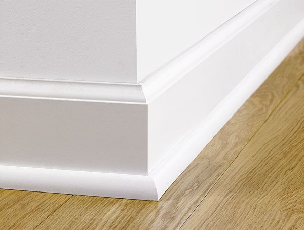 White baseboard moulding installed above wood flooring